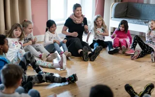 Pedagog med barn i en ring som gör musikaliska övningar.
