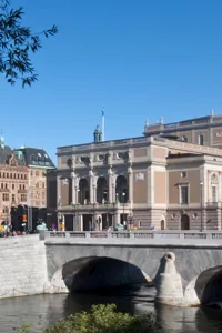 Large buildings against a blue sky, in the foreground a stream of water.