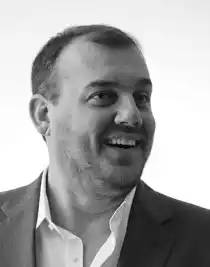 A close-up of a man with a big smile, he is looking out to the right.