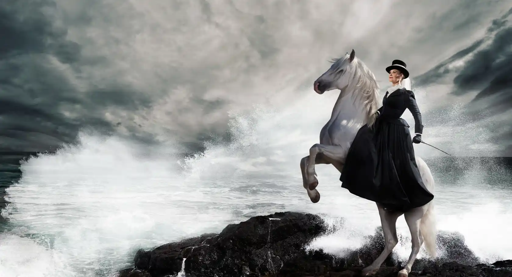 A woman riding a white horse on top of a rocky cliff.