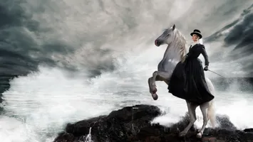 A woman riding a white horse on top of a rocky cliff.