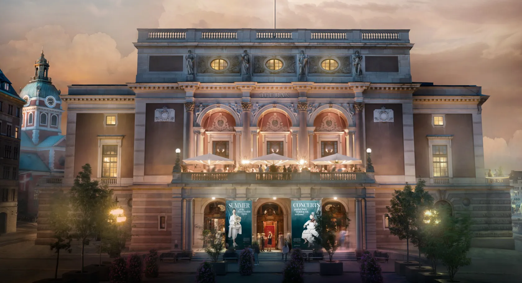 En stor fasad med träd framför som badar i sommarkvällsljus, i bakgrunden en kyrka.