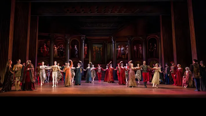 A large number of dancers stand on a stage in various poses.