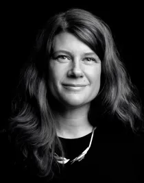 A close-up of a woman with flowing dark hair and a distinctive necklace.