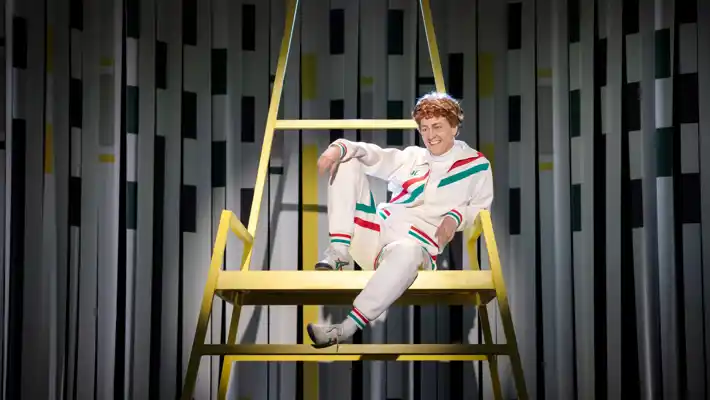 A man with a mocking smile sits relaxed in a high chair.