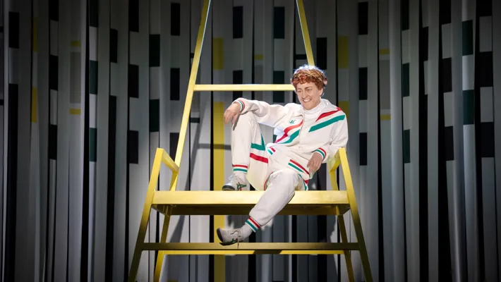 A man with a mocking smile sits relaxed in a high chair.