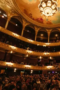 An ornate multi-story auditorium, full of people.