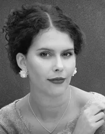 A close-up of a dark-haired woman with her hair up, wearing a necklace and earrings.