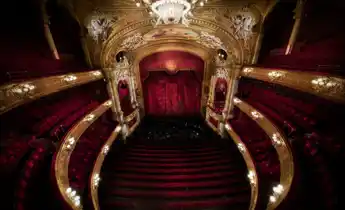 Vy mot en scen från en rikt utsmyckad salong i rött och guld.