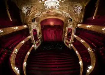 View of a stage from a richly decorated auditorium in red and gold.