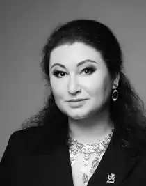 A close-up of a woman with dark, updo hair wearing large jewelry.