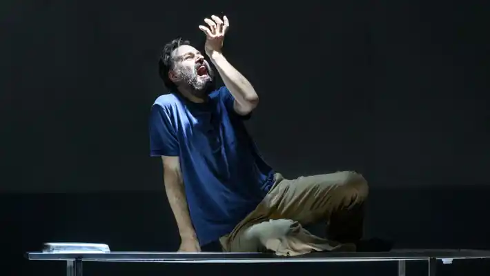 A man sitting on a bench under a light.