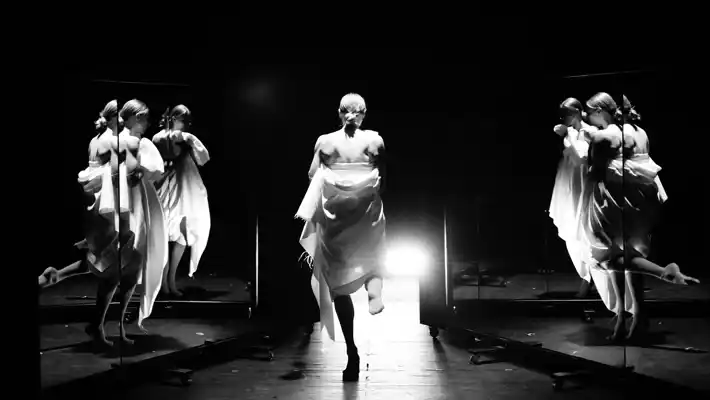 A female dancer dances with her back to the camera, seen from the sides in different mirrors.