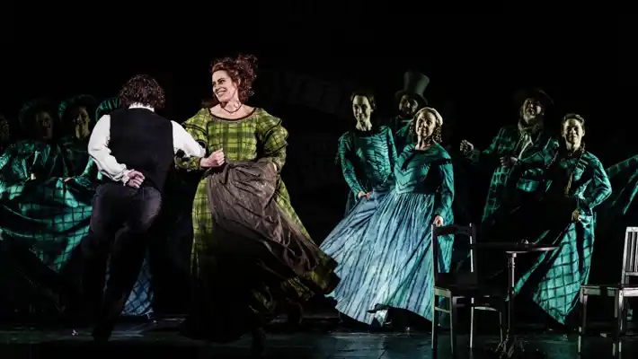 A group of people on a stage, a couple dancing in the foreground.