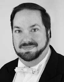 A close-up of a man with a beard wearing a tailcoat.