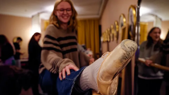 A woman smiles as she puts her foot against a barre.