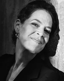 Black and white image of a woman with her head slightly tilted against a wall.