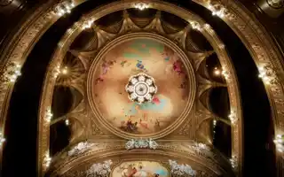 View of a roof and several balconies, a large ceiling painting and a magnificent chandelier in the center.