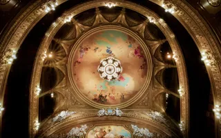 View of a roof and several balconies, a large ceiling painting and a magnificent chandelier in the center.