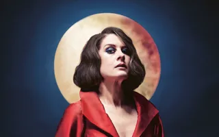 A woman in a red dress stands against a dark blue background, a moon shining behind her head.