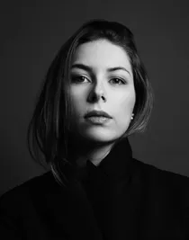 Close-up of a woman with dark hair wearing a dark jacket.