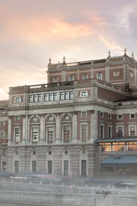 A large house by a stream, a church in the background, a light fog around the buildings.