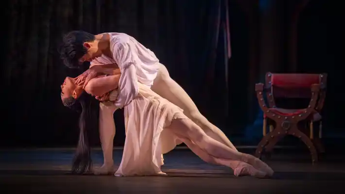 Two dancers, a man and a woman, in a tender movement where he holds her in his arms.