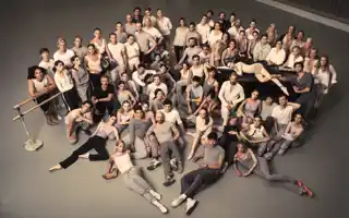 A large group of people sitting and standing, gathered in a cluster.