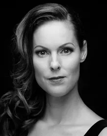 A close-up of a woman with long, wavy, dark hair over one shoulder.