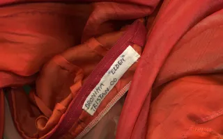 Detalj av kostym i rött tyg med en namnlapp.