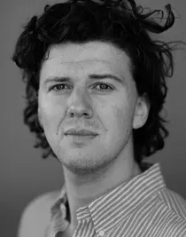 Close-up of a man with bushy hair and a striped shirt.