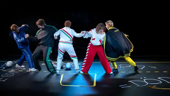 Five people arm in arm pulling each other.