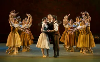 On a stage, you see a young couple in the middle, surrounded by several female dancers.