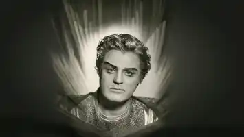 A black-and-white portrait image of a man in a suit, behind him candle flames.