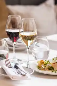 A set table with food and wine in tall glasses.