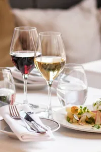 A set table with food and wine in tall glasses.