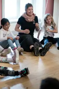 Pedagog med barn i en ring som gör musikaliska övningar.
