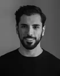 Portrait image of a smiling dark-haired man with a beard, wearing a dark shirt.