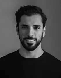 Portrait image of a smiling dark-haired man with a beard, wearing a dark shirt.