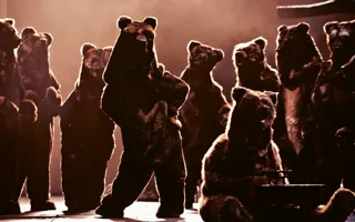 Several bears on a stage, one dancing, one playing a carillon.