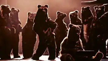 Several bears on a stage, one dancing, one playing a carillon.