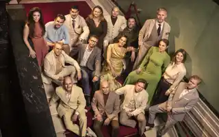 Several people are standing on a staircase, looking up at the camera.