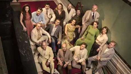 Flera personer står uppställda i en trappa, de tittar upp mot kameran.