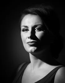 A close-up of a woman wearing dark and a low-cut top.