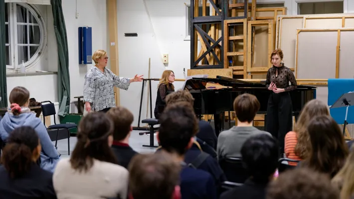 A group of people in a room with a piano.