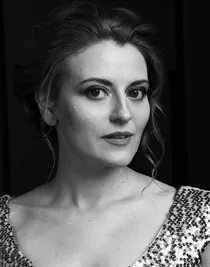 A close-up of a woman with updo, curly hair, wearing a sequined top.