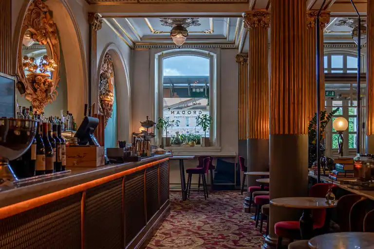 Ett rum med en lång bardisk till vänster och stolar och bord till höger.