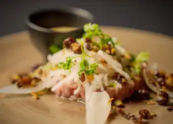 Närbild på mat, i bakgrunden en liten bägare med en sås.