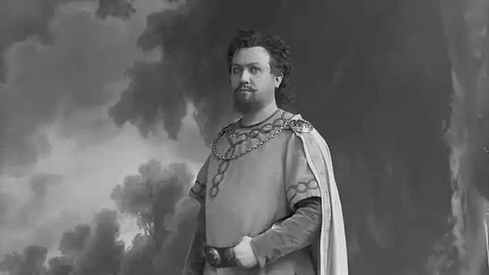 A man in historical costume stands in what appears to be a backdrop.